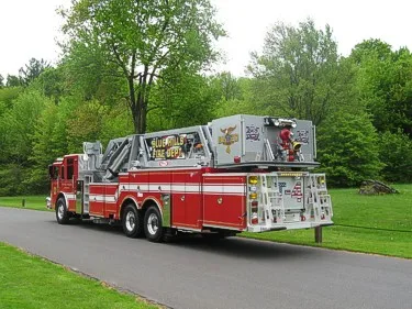 Rear right side view showing side compartments, tandem rear wheels, and rear bucket assembly.
