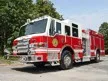 Wide front-right view of the pumper parked roadside with full side body visible.