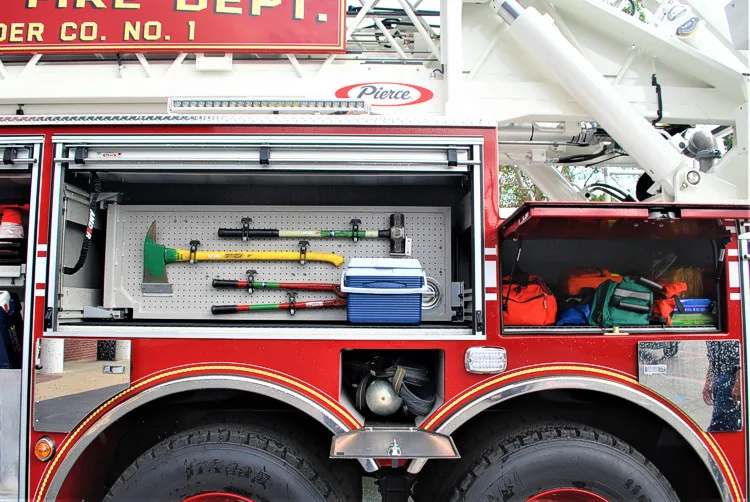 Open side compartment showing mounted tools and shelf storage by tandem wheels