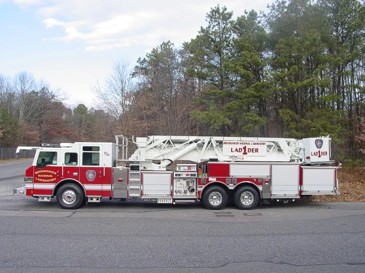 Driver-side full profile showing stowed aerial ladder sections, side compartments, and tandem wheelbase.