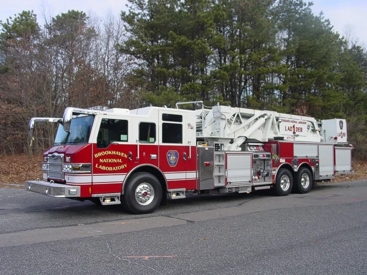 Front-left wide view of the tower ladder showing cab face, side body, and ladder base section.
