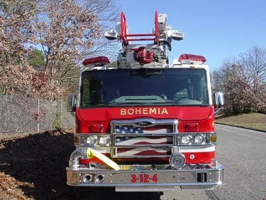 Head-on front view showing grille, windshield, warning lights, and aerial nozzle assembly above the cab.