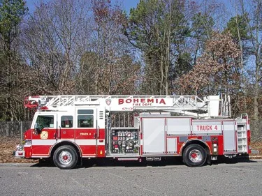 Driver-side full profile showing the stowed aerial ladder, pump panel controls, and side compartments.