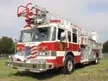 Aerial ladder truck front-left exterior view showing enclosed cab and ladder sections
