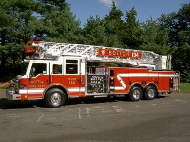 Driver-side full profile showing ladder bed, pump panel, and tandem rear axles