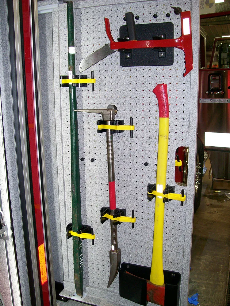 Open narrow compartment showing mounted hand tools in vertical slots