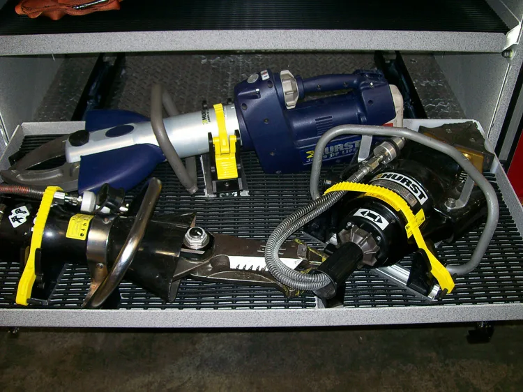 Open compartment close-up showing hydraulic tools and hose lines