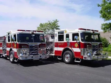 Pumper pair front-left profile showing apparatus lineup in lot