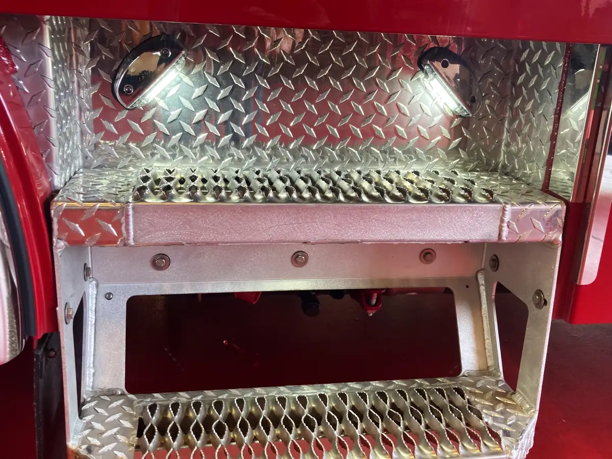 Underbody step storage compartment close-up with diamond-plate trim