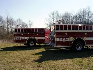 Side view of two pumpers showing long hosebed rails and rear wheel areas