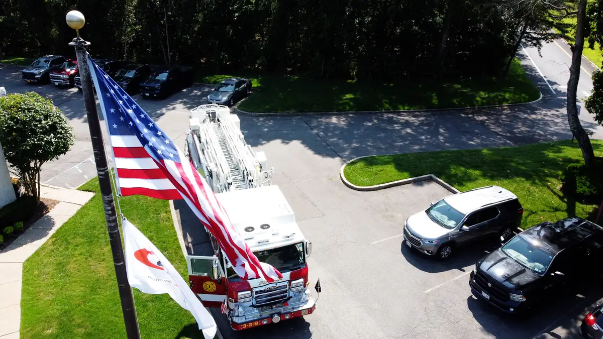 Pierce tower ladder aerial view with large flags in foreground and front cab visible