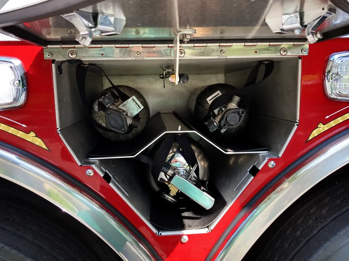 Narrow rear body compartment open showing mounted extinguisher and vertical storage