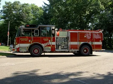 Driver-side full profile of a pumper showing pump panel controls and side compartments.