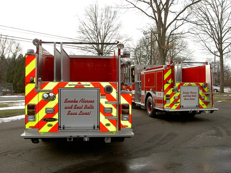 Rear view of two apparatus showing chevrons and rear body panels