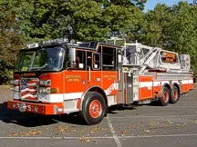 Tower ladder truck front-left profile showing cab and full side body