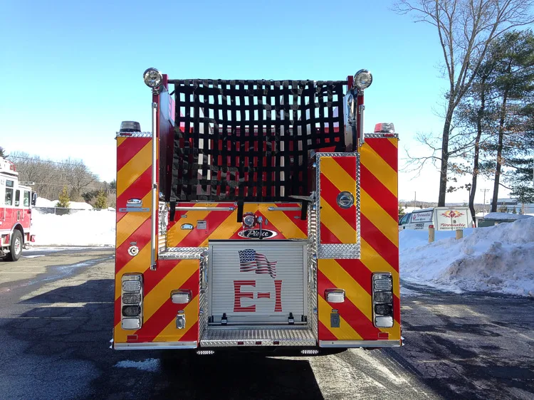 Straight rear view with red-yellow chevrons, rear hosebed netting, and center rear compartment door.