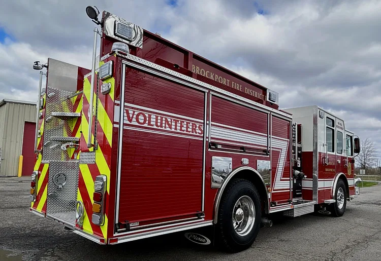 Rear-left exterior view showing chevron striping, rear warning lights, and side body panel