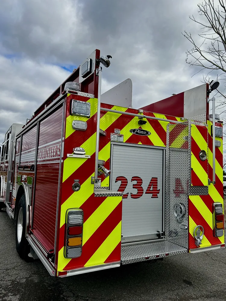 Rear-left close view showing chevron striping, rear compartment door, and warning lights