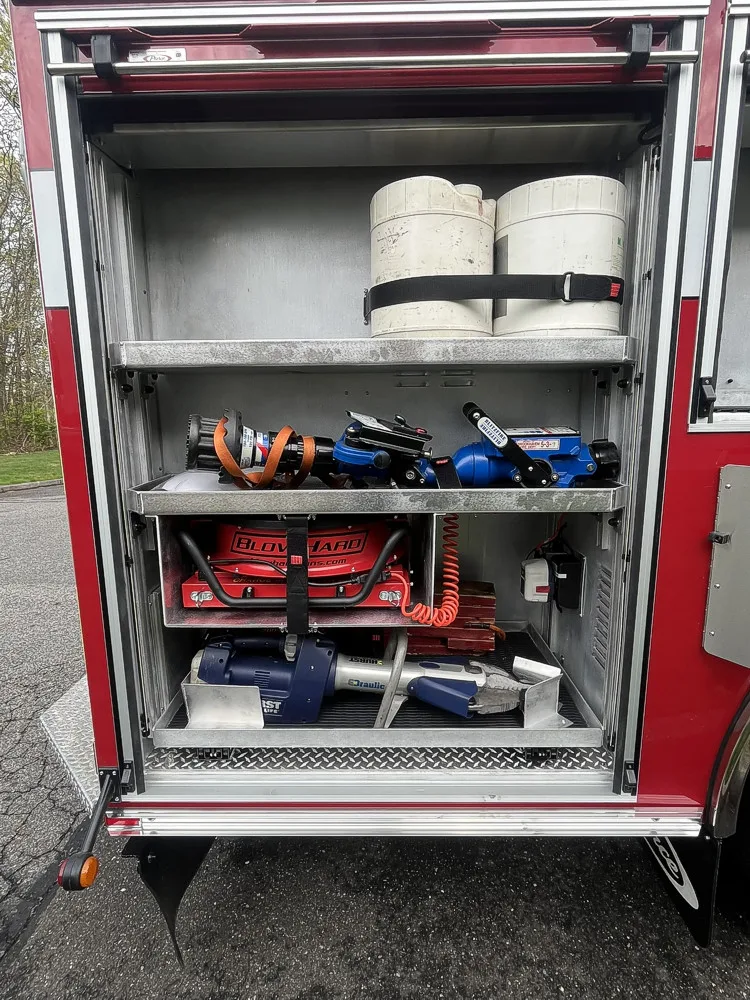 Open side compartment showing hose rolls, cribbing blocks, and hydraulic rescue tool storage