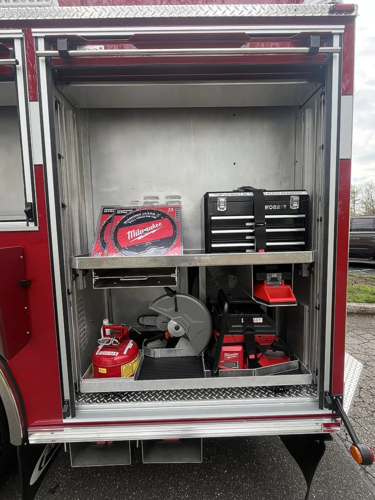 Open side compartment with saw blades, tool chest, cutoff saw, and fuel can