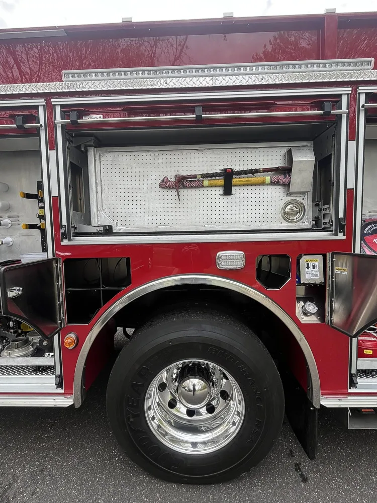 Open side compartment with hose rolls, cribbing blocks, and hydraulic rescue tool on pull-out tray