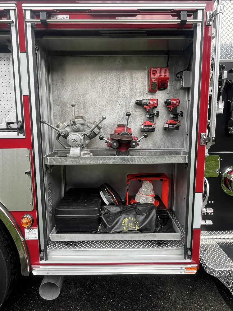 Open side compartment showing hand tools, cordless drills, and charger storage