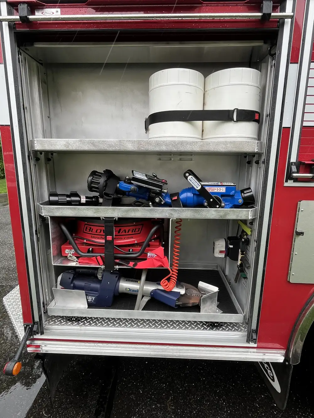 Open side compartment showing nozzles, handline tools, and shelf-mounted equipment