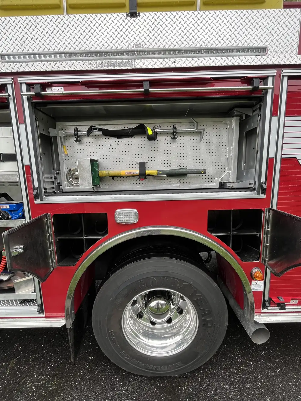 Open upper compartment above rear wheel showing mounted hand tools and wheel area