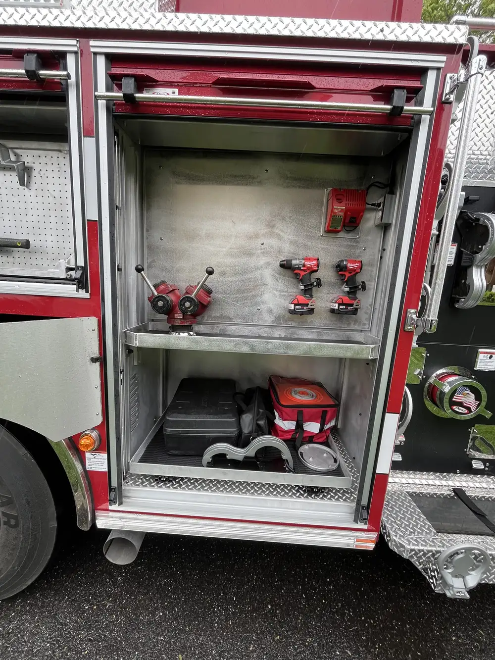 Open side compartment showing cordless tools, chargers, and equipment bags