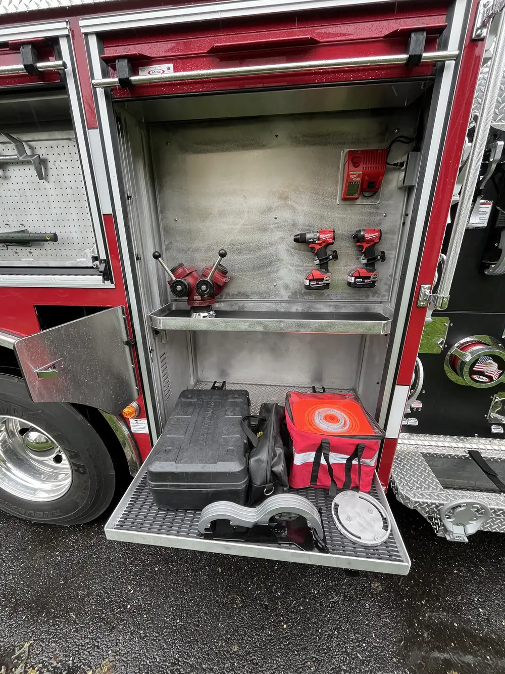 Open compartment with pull-out tray showing cordless tools, tool case, and equipment bag