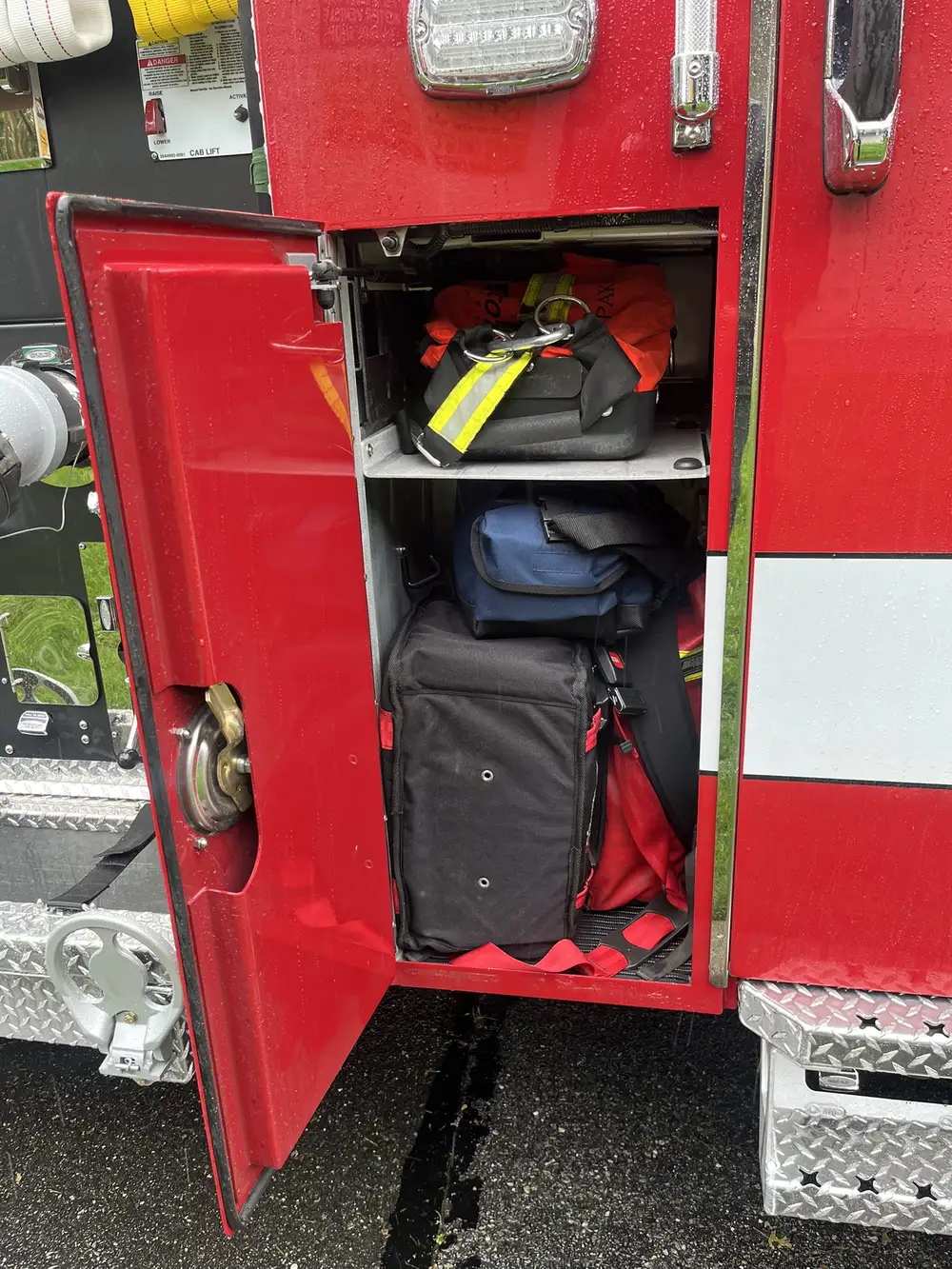 Narrow side compartment showing stacked equipment bags and lower shelf storage
