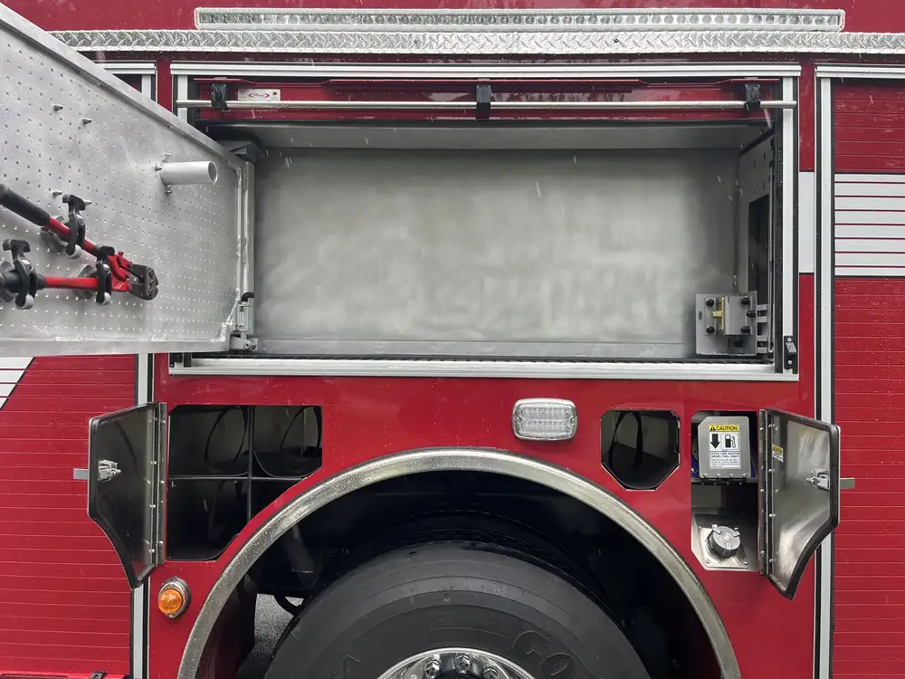 Open upper compartment above rear wheel with door-mounted cutters and empty storage space