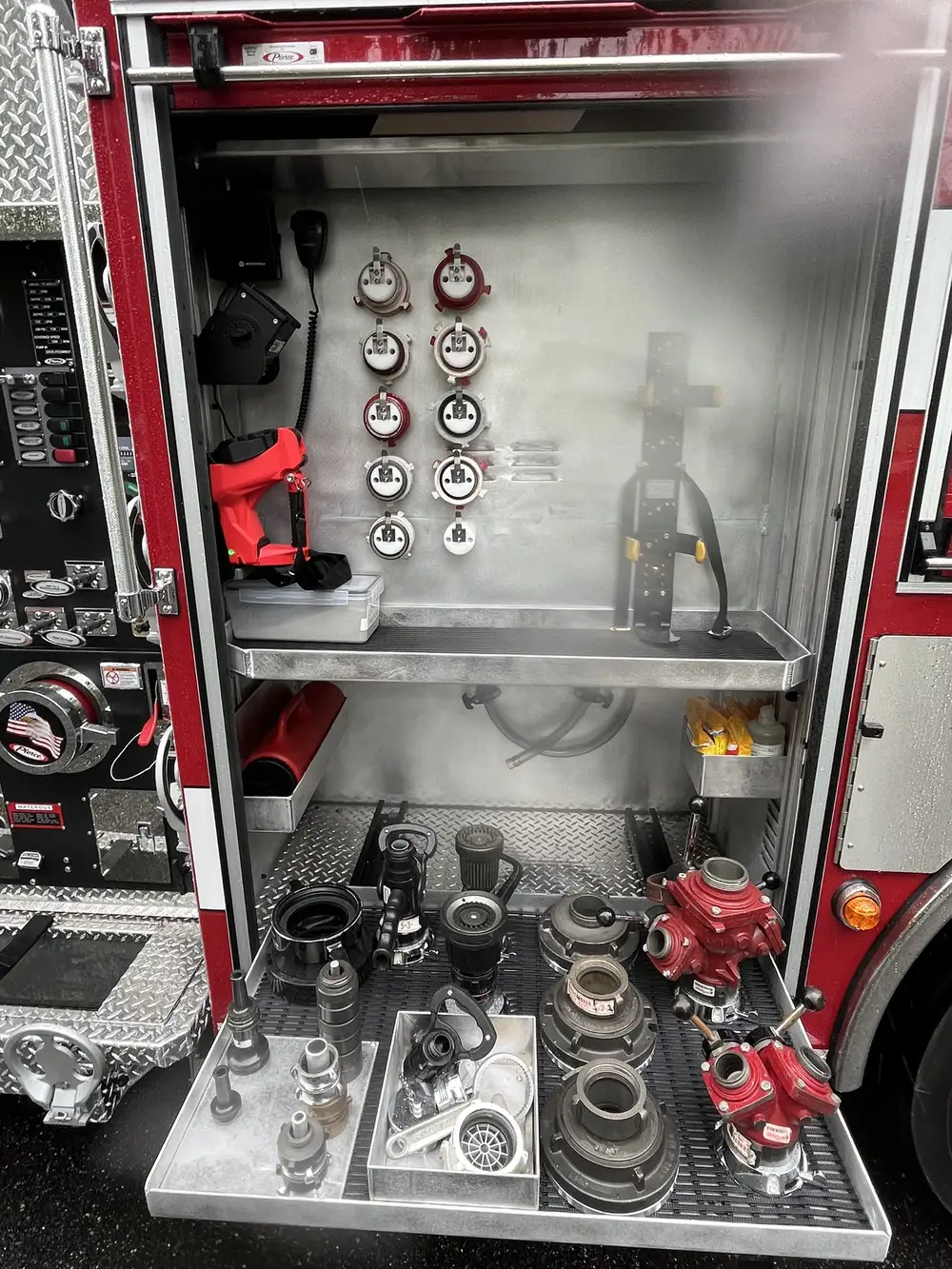 Open compartment with pull-out tray showing adapters, valves, and hose couplings