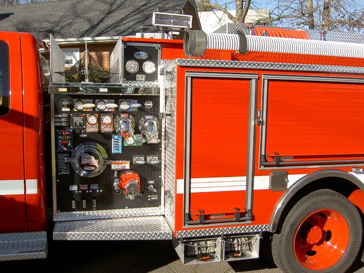 Pump panel close-up showing gauges, valves, and intake controls beside rear wheel