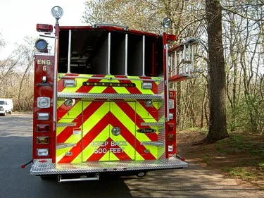 Rear view showing open hosebed area, chevron striping, and rear warning lights