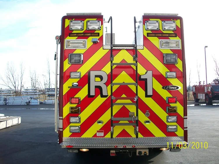 Straight rear view with red-yellow chevrons, center rear ladder, and rear warning lights.