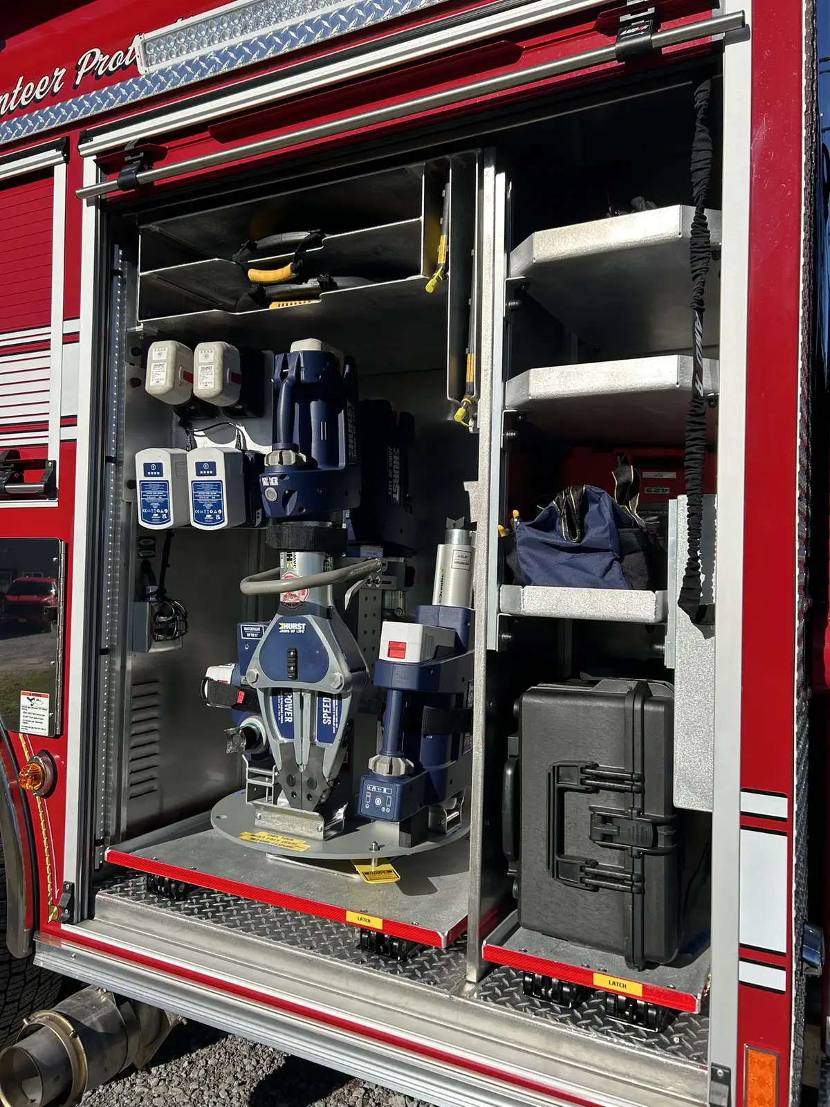 Open side compartment showing battery extrication tool, chargers, and storage shelves