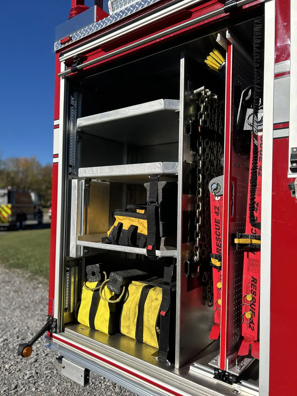 Rear side compartment doors open with storage shelves and yellow gear bags