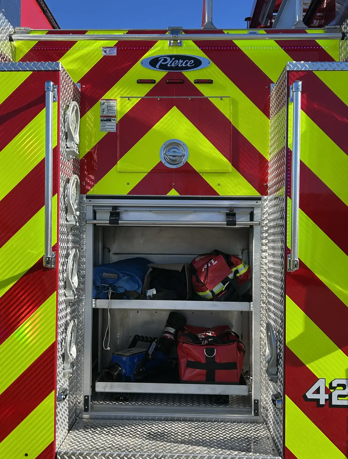 Pierce pumper rear-right exterior view with chevron striping and open rear bay