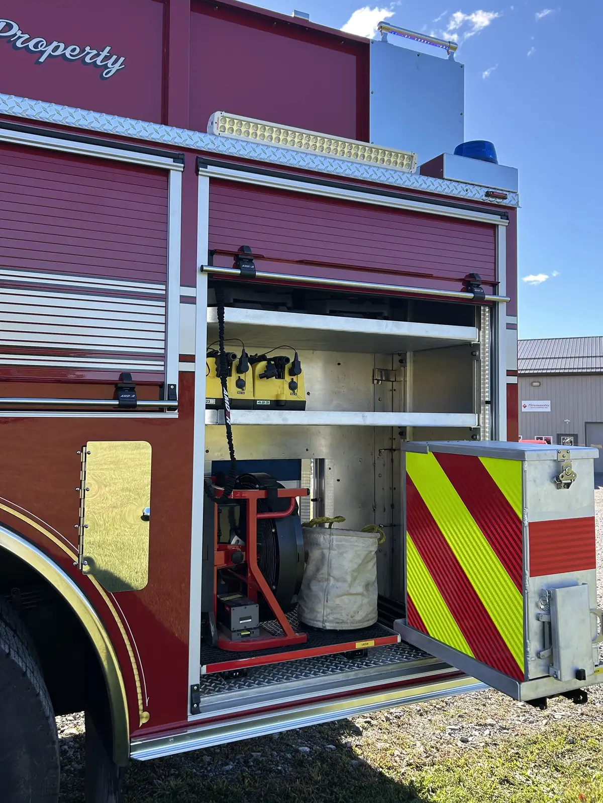 Open side compartment showing long-handled tools, saws, and equipment storage