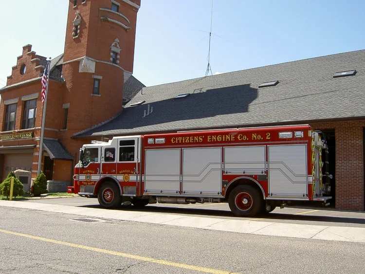 Driver-side profile view showing full pumper body beside station building