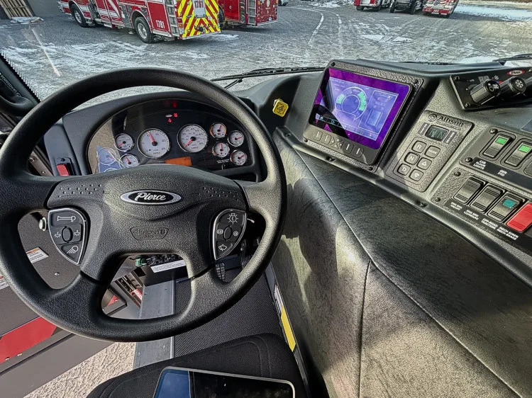 Driver cockpit close-up showing steering wheel, digital cluster, and tablet display
