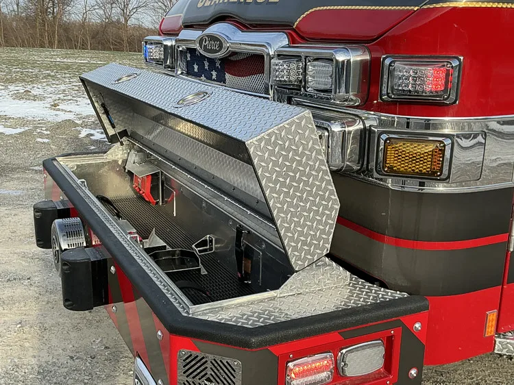 Front bumper compartment open showing storage bin and mounting brackets