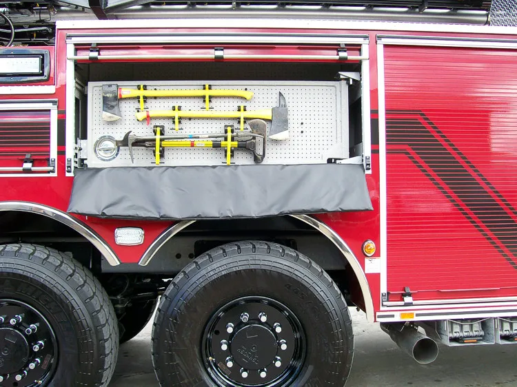 Open side compartment showing mounted long tools above tandem rear wheels