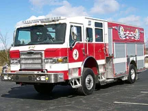Wide front-right view of the rescue pumper parked in the lot with full side body visible.