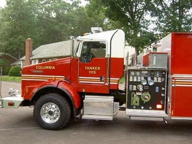 Driver-side profile close-up showing cab, side pump controls, and front wheel