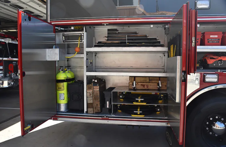 Open side compartment showing shelves with tool cases and equipment bins