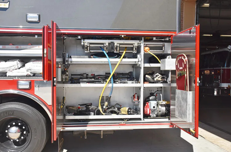 Open full-width side compartment showing tools, hoses, and shelf-mounted gear