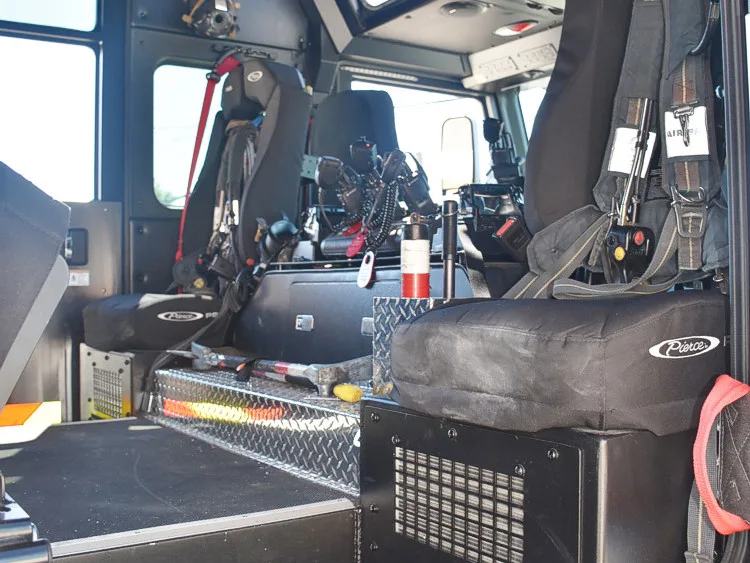 Cab interior side view showing front seats, center console, and mounted radios
