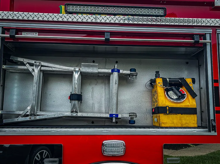 Open side compartment showing hand tools, nozzles, and shelf storage